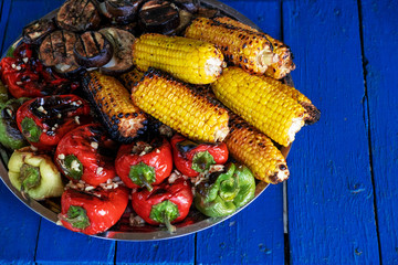 Grilled vegetables on plate on wooden background. Pepper, corn and eggplant cooked on grill. BBQ. Barbecue. Organic salad
