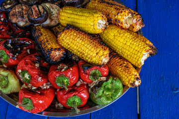 Grilled vegetables on plate on wooden background. Pepper, corn and eggplant cooked on grill. BBQ. Barbecue. Organic salad