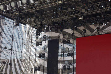 Stage for concert or show under blue sky. Light equipment with illuminated spot and LED lights. Sound and video equipment on metal frame construction installed outside