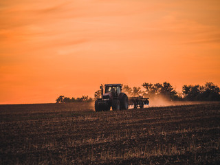 Tractor on filed by sunset.