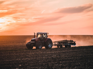 Obraz premium Tractor on filed by sunset.