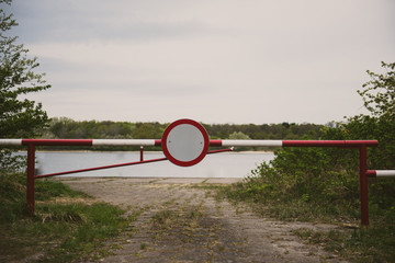 the barrier with a no entry sign . Road leads to the river