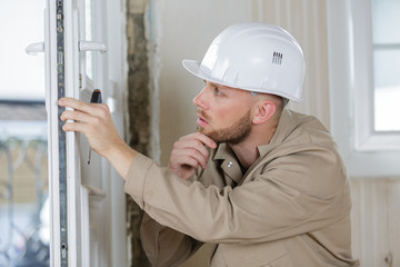worker in overalls installing a window