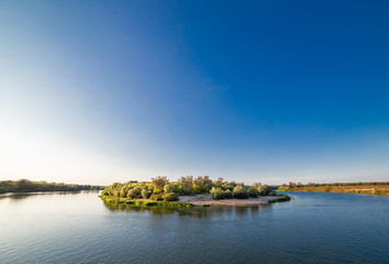 Island on the river against the blue sky at sunset.