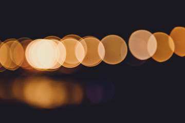 Colorful city lights with bokeh effect reflected over sea background at dusk