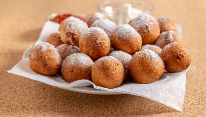 Round doughnuts, sprinkled with powdered sugar, lie on a plate