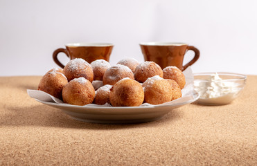 Round doughnuts, sprinkled with powdered sugar, lie on a plate