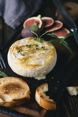 Camembert cheese with crackers, figs and herbs