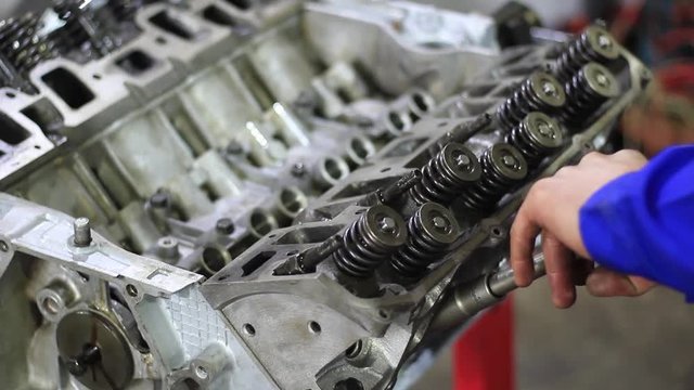 Mechanic hands tighten nut with wrench while repairing engine