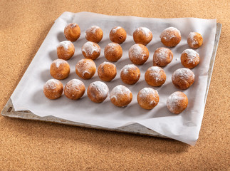 Donuts sprinkled with powdered sugar lie on a baking sheet. Textures.