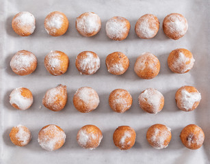 Donuts sprinkled with powdered sugar lie on a baking sheet. Textures.