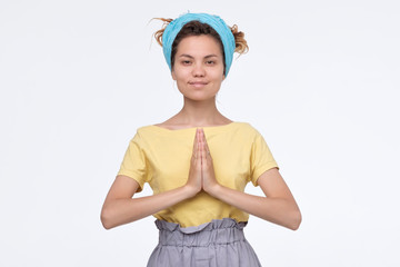 Girl keeps palms together smiling welcoming her friends in namaste gesture. S