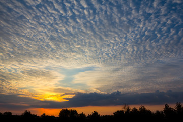 Fototapeta na wymiar dramatic sunset scene, sun rays push through a cumulus clouds over forest silhouette, natural background