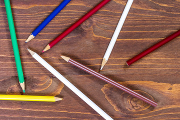 Fototapeta premium colored pensils on a brown table. drawind on a wooden background
