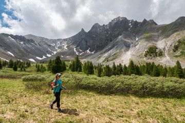 Tourist girl goes hiking in Eastern Sayan Mountains