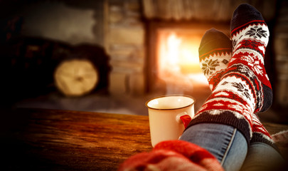 Fototapeta na wymiar Fireplace and slim woman legs with christmas socks 