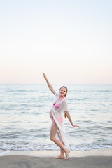 Fototapeta na wymiar Young pregnant woman dancing on the seashore. Enjoying the moment.