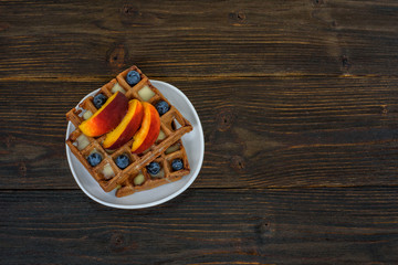 Chocolate Belgian waffles with fruits and berries. Delicious breakfast. Wooden background. Top view, copy space