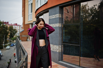 Obraz premium A tall leggy young beautiful and elegant model woman at claret coat.