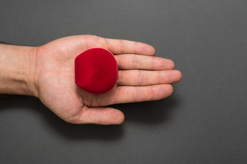Open male palm with a red jewelry box. Present. Black background