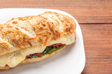 Beef steak sandwich with cheese and tomato, isolated on wooden background