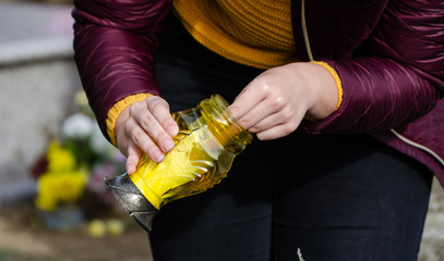 Women light a yellow candle to put it on a tombstone - all souls day preparing in the cemetery