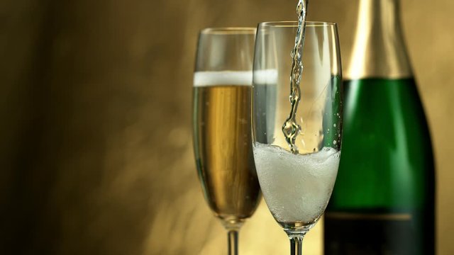 Super slow motion of pouring Champagne wine into glasses, closeup view. Filmed on high speed cinema camera, 1000fps