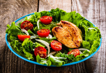 Salad with chicken breast and vegetables on wooden table