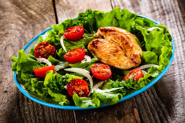 Salad with chicken breast and vegetables on wooden table
