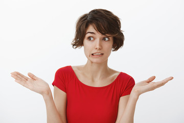 Yikes how embarrassing sorry. Awkward cute silly attractive woman short haircut grimacing perplexed unsure have doubts shrugging hands spread sideways unaware puzzled answer stand white background