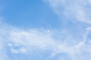 Daytime skies with colorful moon and light cloud for use as a background.