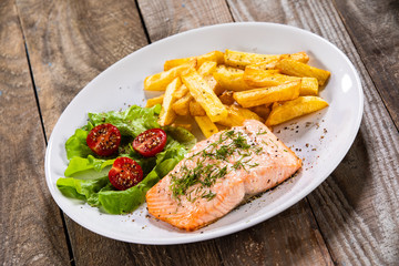 Fried salmon with french fries on wooden table