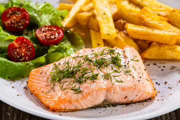 Fried salmon with french fries on wooden table