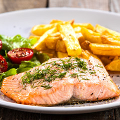 Fried salmon with french fries on wooden table