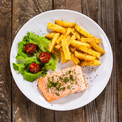 Fried salmon with french fries on wooden table