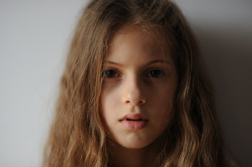 portrait of pensive serious beautiful little caucasian girl with long hair and serious face