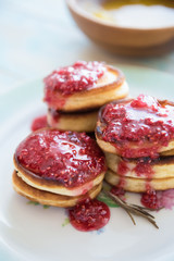 Pancakes with raspberries jam on plate on wooden table. Stack of pancakes for breakfast
