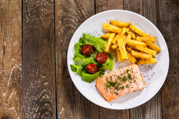 Fried salmon with french fries on wooden table