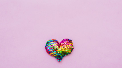 Colorful heart made of sequins on a pink background. Copy space