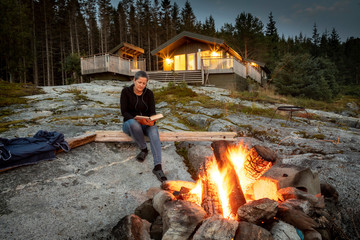 woman reading beside campfire in norway