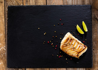 Fried cod loin on black stone plate