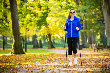 Obraz premium Nordic walking - middle-age woman working out in city park