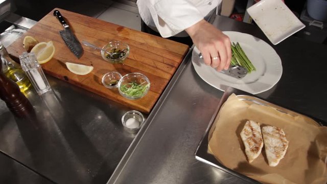 The process of serving grilled pike perch fillet with asparagus and lemon