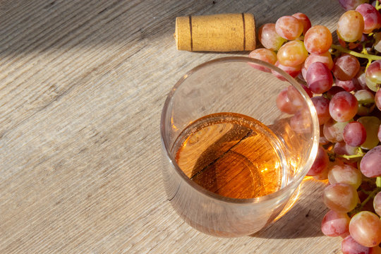 bicchiere di vino grappolo di uva rosa e tappo di sughero su fondo legno