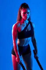 Fototapeta na wymiar beautiful pleasant woman having a rest after cross fit exercise. isolated blue background, stsudio shot