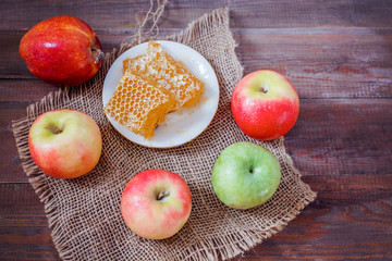 Honeycombs with honey and slices of ripe apples on wooden table.