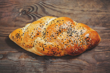 Challah with sesame seeds on wooden background