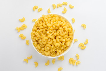 Dried corneti rigati Italian pasta in a round bowl ready to be cooked, isolated on a white table, with view from above 