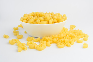 Dried corneti rigati Italian pasta in a round bowl ready to be cooked, isolated on a white table, side view
