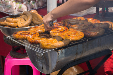 Northern Thai spicy sausage (Sai Aua) grill on grates in street food market. Selective focus.
